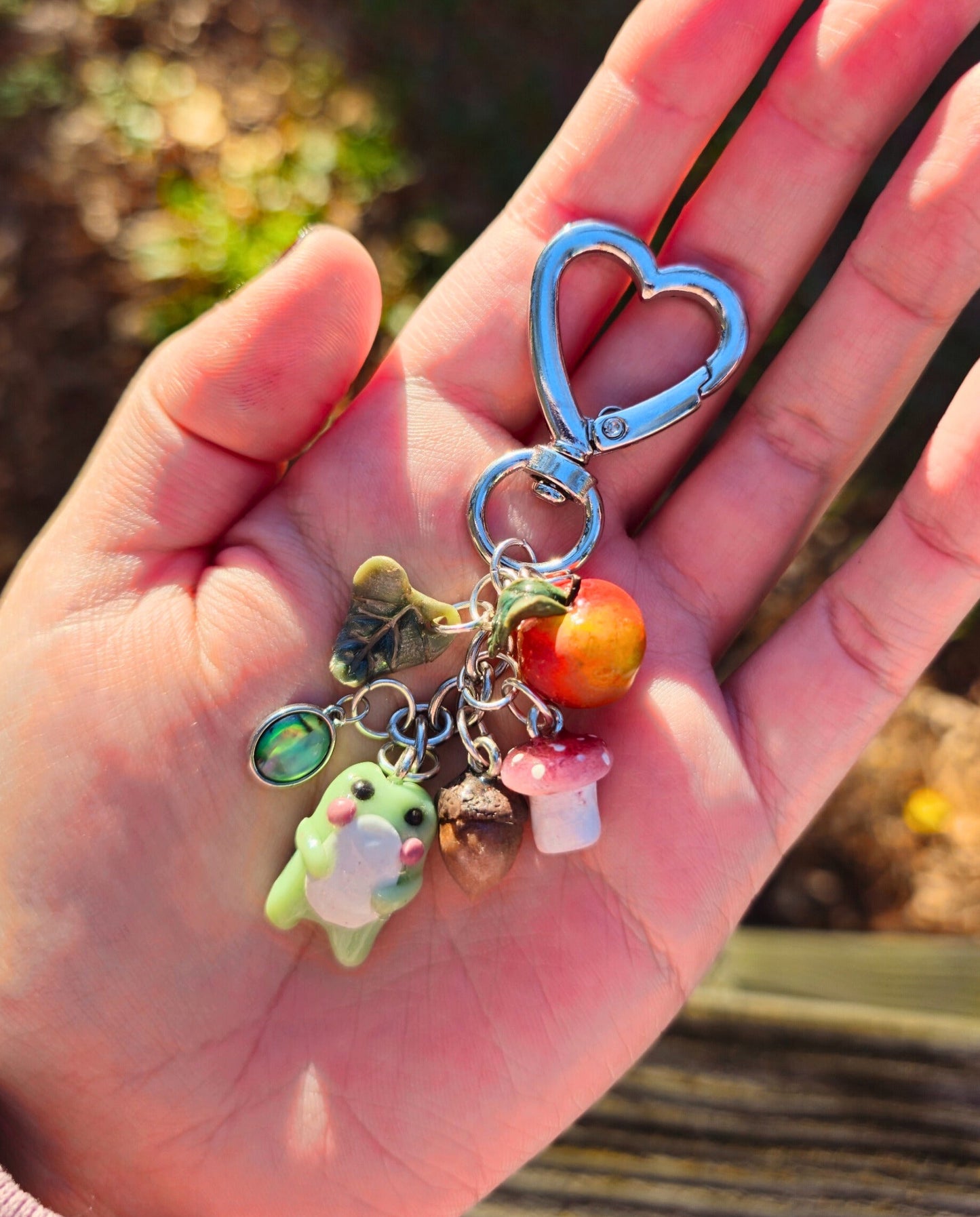 Hand holding a keychain with colorful charms against a blurred natural background