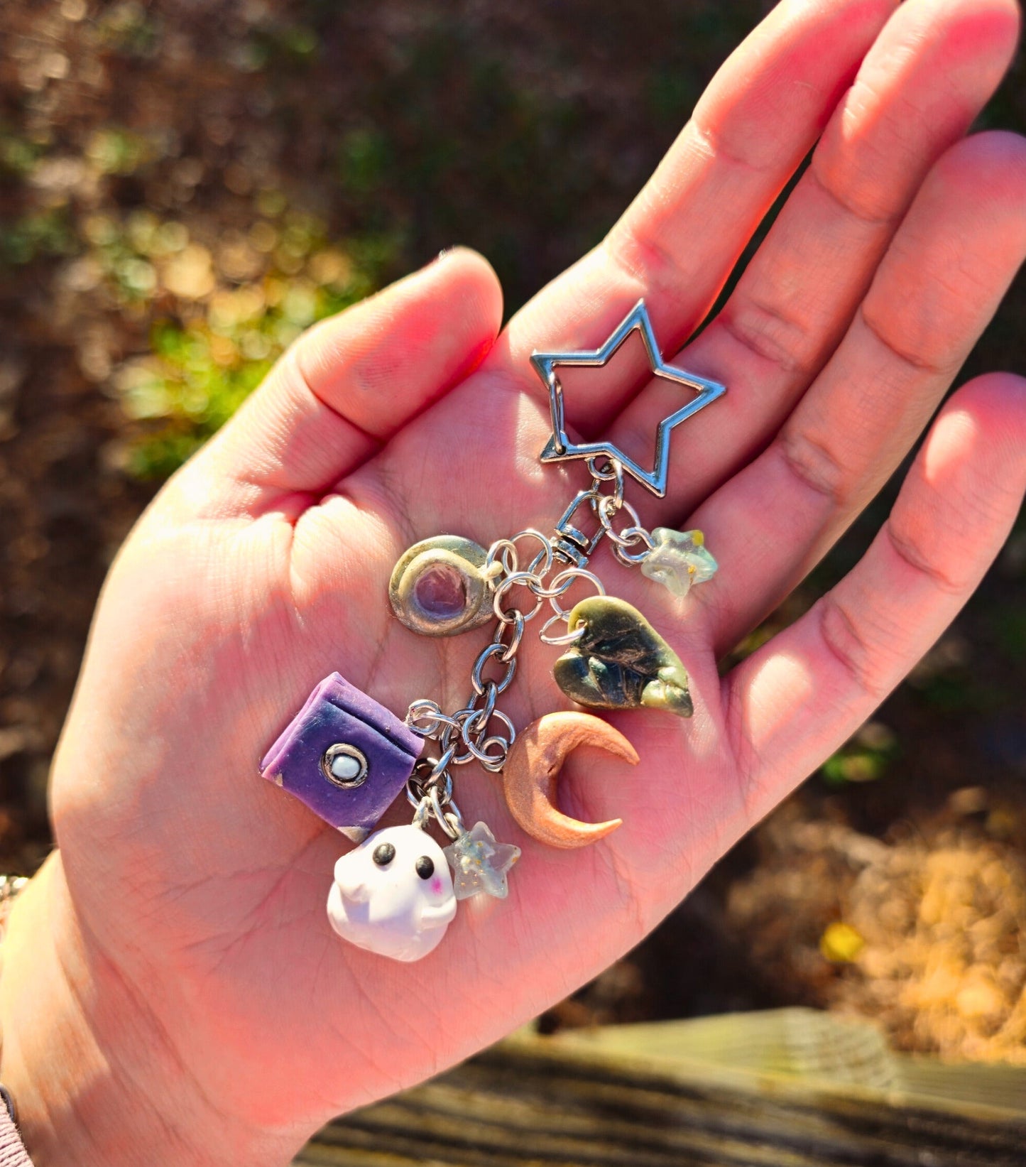 Hand holding a keychain with various charms against a natural background